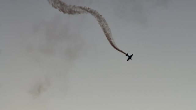 Silhouetted jets performing aerobatic maneuvers with smoke trails