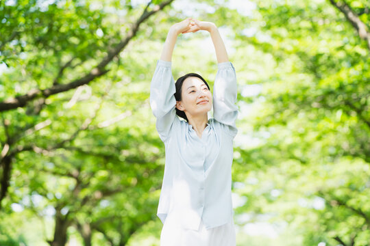 木の下でストレッチをする若い女性　ライフスタイルイメージ