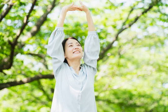 木の下でストレッチをする若い女性　ライフスタイルイメージ