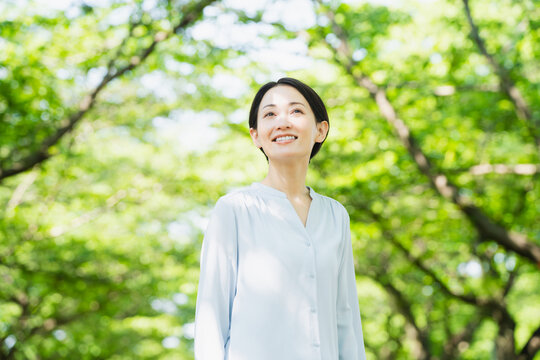 並木で見上げている若い女性　ライフスタイルイメージ