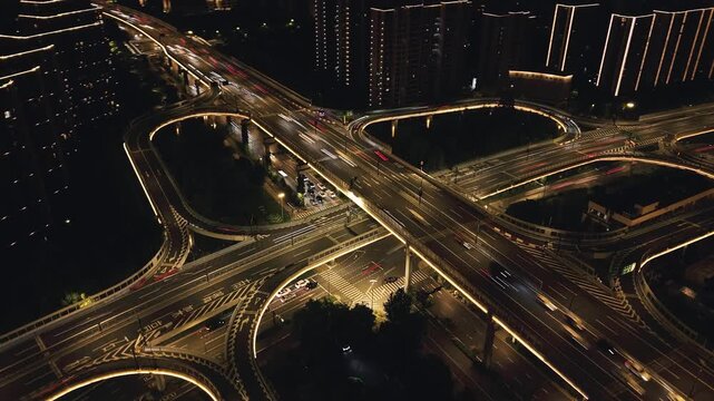 Aerial view captures a busy Hangzhou highway interchange at night with glowing lights and towering apartments