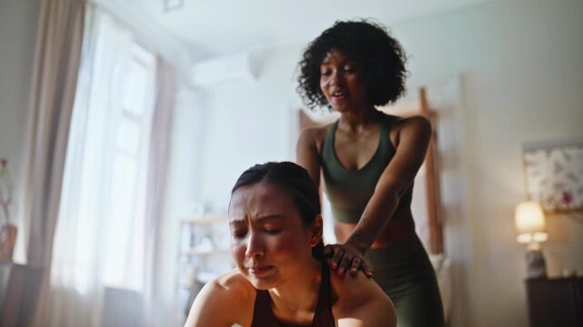 Personal trainer helping tired woman deep stretch home workout. Coach session.