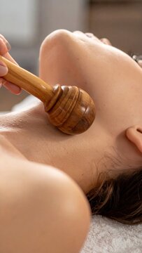 Wood therapy facial massage using a wooden tool for lifting and contouring the neck and chin area in a spa