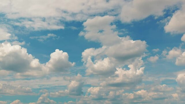 White puffy clouds drifting across a bright blue sky during a sunny afternoon capturing nature in motion