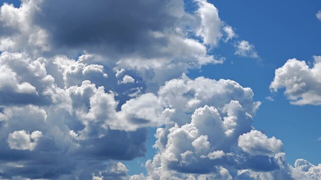 Puffy cumulus clouds drifting across a blue sky, peaceful weather scene, airy atmosphere, summer.