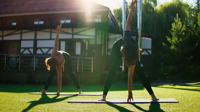 Elderly women practicing slow motion Pilates stretches outdoors on yoga mats, focusing on flexibility, balance, and gentle mindful movement in warm sunlight