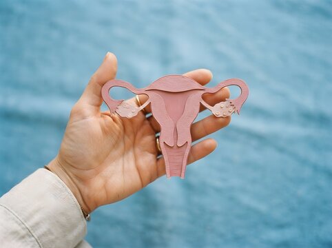Female Reproductive Health Concept with Woman Holding Paper Uterus on Blue Background. Gynecology, Fertility, Women&rsquo;s Healthcare and Reproductive Awareness