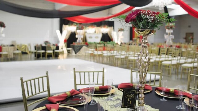Numbered table five is arranged with guest seating and decorations inside a prepared quinceanera reception hall.