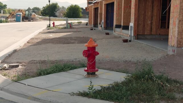 Slow right-to-left tracking shot of a red fire hydrant beside new homes under construction.