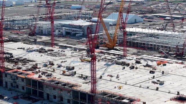 Aerial close view of cranes working above a concrete building deck at a major construction site