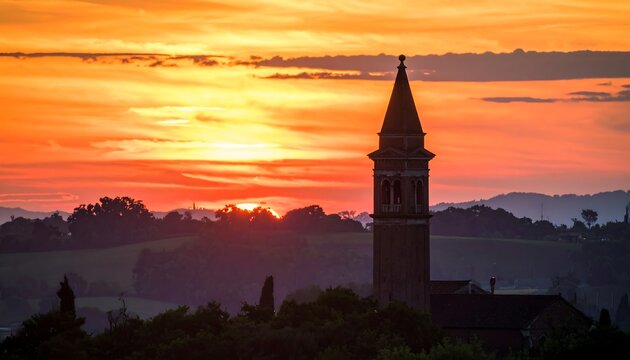 Tower silhouette against a fiery sunset over rural landscape