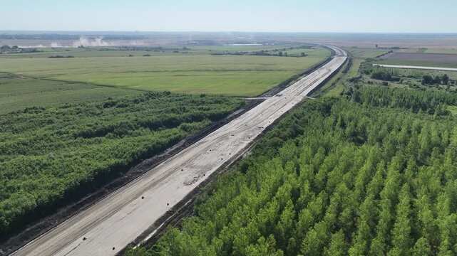 Highway infrastructure project with earthworks, soil compaction and gravel transport for modern civil engineering. Aerial view of highway construction site 
