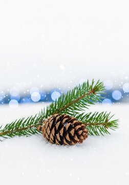 A rustic pine cone and fresh green fir branch rest on a blanket of soft white snow with gentle falling snowflakes and blue bokeh lights, fir, coniferous, seasonal