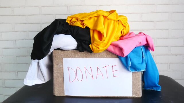 Pile of clothes in donation box with sign saying donate
