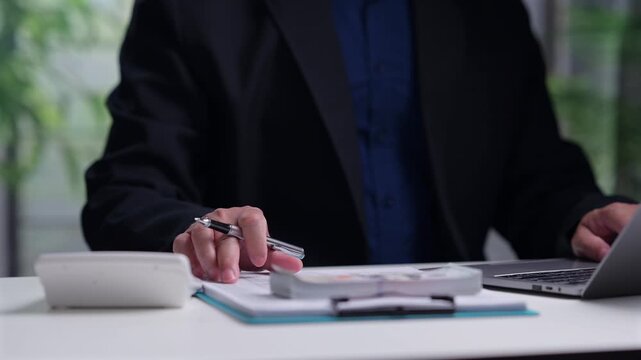 Businessman wears suit, types laptop keyboard, calculates financial budget, plans tax investment, manages corporate cash flow, organizes business account paperwork, counts money.