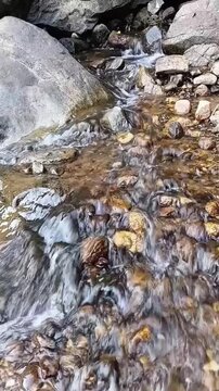 Vertical shot of clean fresh water stream flowing downward from Diyaluma waterfall through dark rocky mountain terrain in Sri Lanka