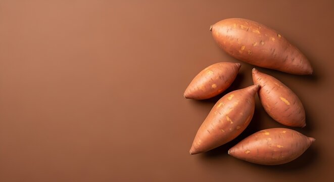 Raw sweet potatoes on brown background. Fresh organic yams for healthy cooking recipes.