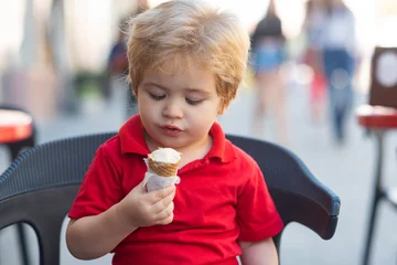 A baby enjoys ice cream on a summer day. Baby licks a sweet ice cream cone. Ice cream brings a smile to the babys face. A baby holds icecream. Baby tastes cold ice cream. Kid happiness. © Volodymyr