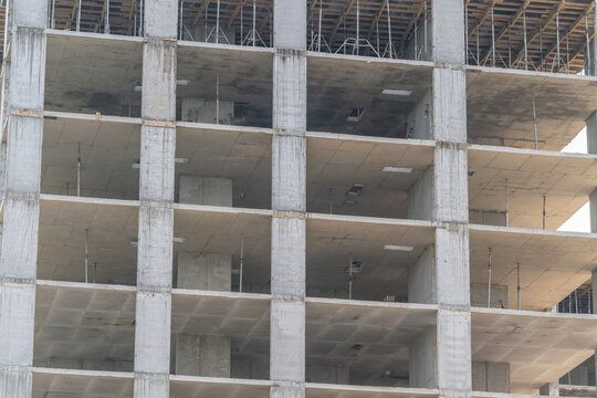 Construction of a multistory building showing concrete columns and unfinished floors in an urban setting during daylight