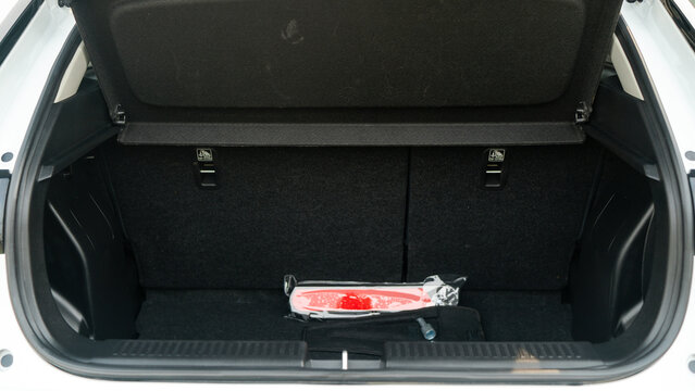 A trunk interior with emergency safety triangle wrapped in plastic, neatly stored against dark fabric lining. Back seats visible in background emphasize practical storage space and preparedness.