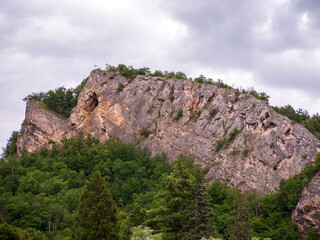 Fototapeta premium Limestone cliffs above Svaty Jan pod Skalou in the Bohemian Karst, Czech Republic, with a summit cross overlooking a protected natural landscape.