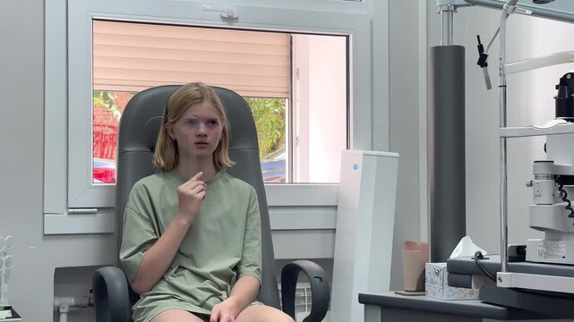 Young girl sitting in an eye clinic for an optometry examination. pediatric eye checkup, vision testing session, medical office setting.