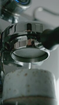 4K Pouring coffee stream from professional machine in cup. Barista man making double espresso, using filter holder. Flowing fresh ground coffee. Drinking roasted black coffee in the morning.