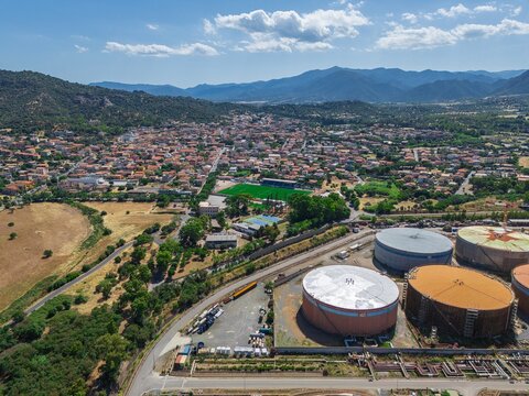 Aerial view of Sarroch village in Sardinia with large industrial storage tanks of Saras refinery