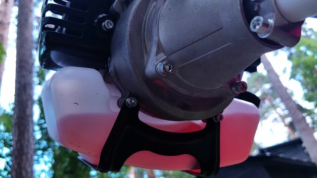 Close up of a gasoline brush cutter engine housing, landscaping machinery, garden equipment, outdoor maintenance, summer season.