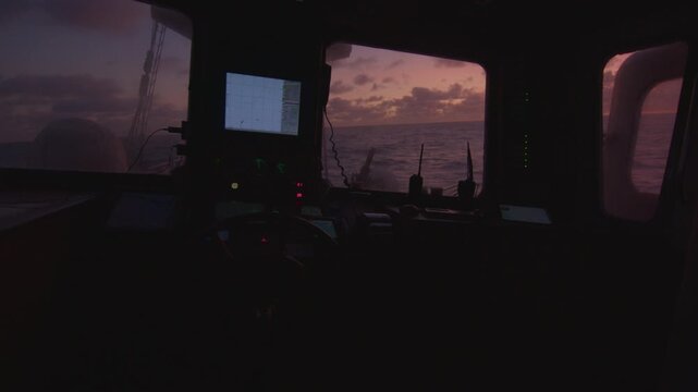 Sunrise in the open sea as seen from the pilothouse of the big sailing boat moving in the Atlantic Ocean under the sails