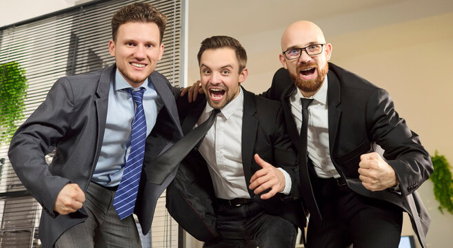 Businessmen team colleagues cheering celebration in office. They celebrate victory and success, showing teamwork, motivation and unity in a modern workspace. Concept of team victory and success.