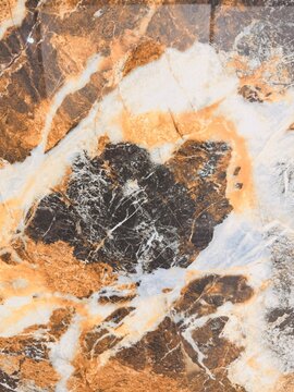 High-resolution close-up of a polished granite floor tile featuring luxurious marble-inspired natural stone textures in black, white, gray, and golden brown.