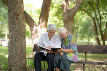 Fototapeta premium Happy Elderly Couple Reading Book Together on Park Bench, Active Aging, Retirement Lifestyle, Family Bonding, Lifelong Learning, and Healthy Senior Living Concept