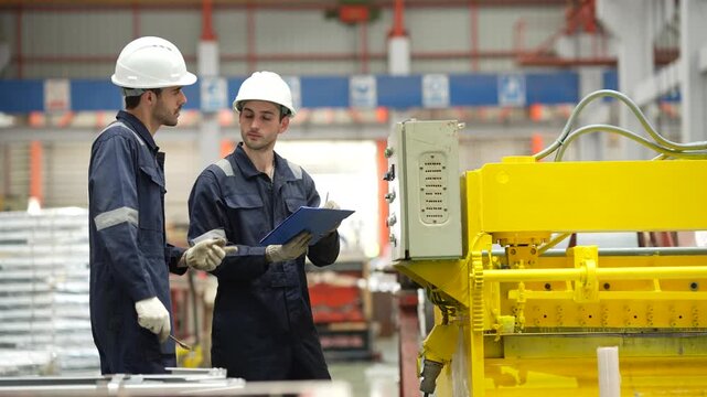 Factory maintenance team inspecting electrical control cabinet during machine servicing in manufacturing plant. Preventive maintenance, industrial engineering and operational reliability.
