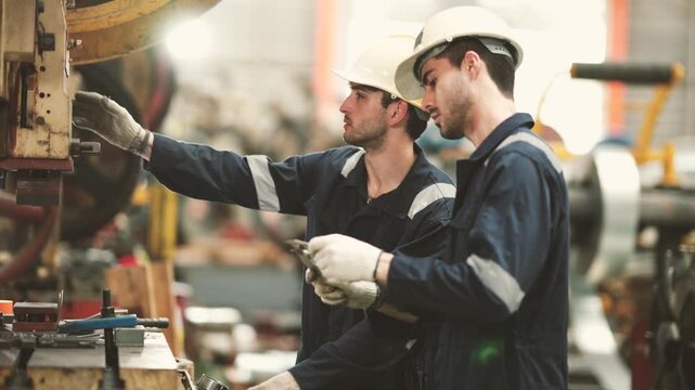 Industrial technicians inspecting metal sheet production equipment inside manufacturing factory. Machine inspection, quality control, maintenance planning and industrial operations.