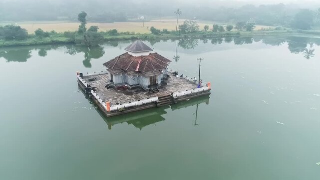 Aerial view of serene Kere Basadi temple floating within varanga Lake heritage landscape scenery