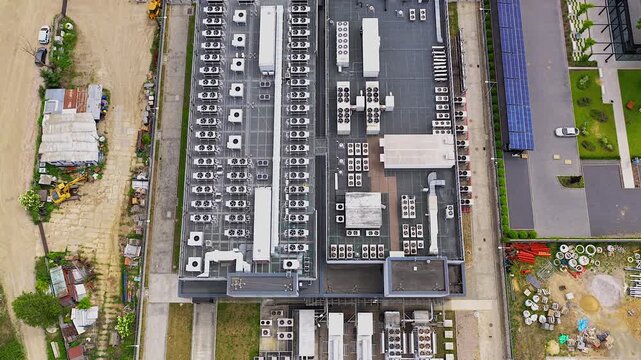 High angle aerial perspective of a modern hyperscale data center rooftop with numerous cooling units and solar panels ensuring energy efficiency