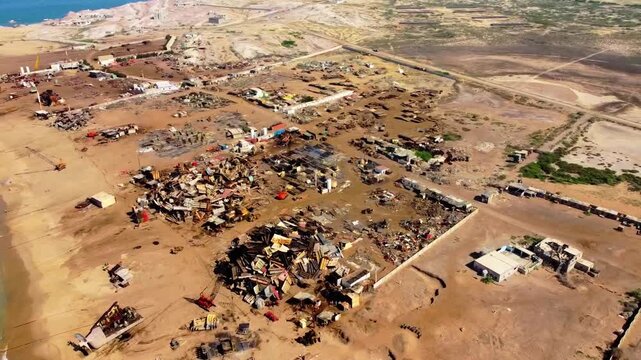 Aerial footage captures cruise ships approaching Gadani Ship Breaking Yard near Karachi, Pakistan, with piles of rusty metal, ship parts, and clear skies highlighting industrial maritime salvage.