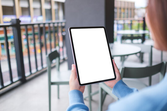 Mockup image of a woman holding digital tablet with blank white desktop screen in cafe