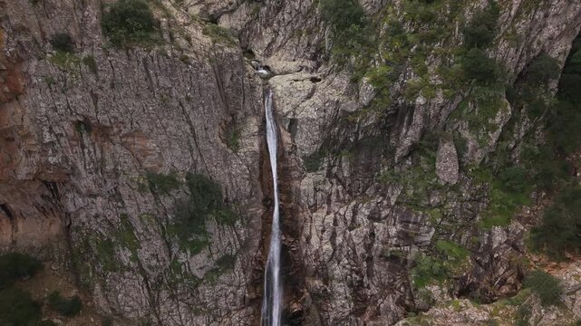 Aerial View Of Piscina Irgas Waterfall Within A Rocky Gorge In Monte Linas Mountains In Villacidro, Sardinia, Italy. - tilt down shot