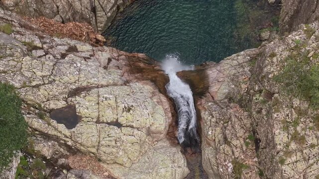 Piscina Irgas Waterfall Over Granite Rock Walls In The Linas Area Of Sardinia, Italy. Aerial top-down shot