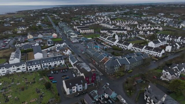 Cinematic aerial drone shot of Barna village in County Galway, Ireland, showing residential housing and coastal landscape under an overcast sky.