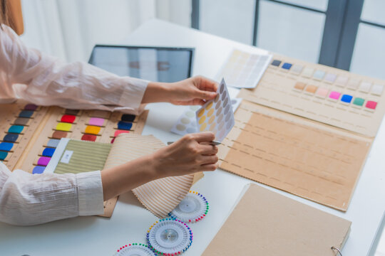 Asian woman designer choosing cloth texture and cloth color