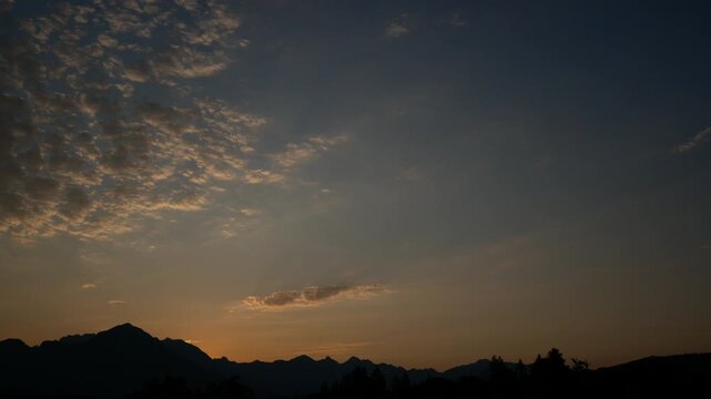 The sun rises at dawn over the mountains with some clouds moving. Sky in the morning video background time lapse