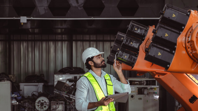 Industrial engineer visually inspecting robotic arm movement and equipment condition during routine production quality evaluation