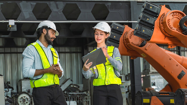 Professional engineers smiling after completing robotic equipment inspection and maintenance activities inside an advanced manufacturing facility