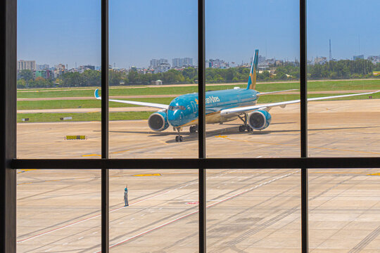 Large glass facade of the terminal showing aircraft boarding bridge at Tan Son Nhat Airport