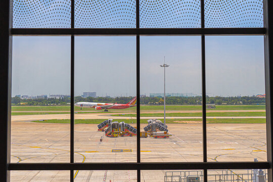 Large glass facade of the terminal showing aircraft boarding bridge at Tan Son Nhat Airport