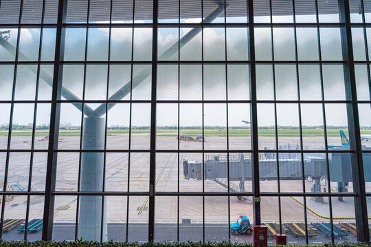 Large glass facade of the terminal showing aircraft boarding bridge at Tan Son Nhat Airport