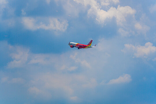 Commercial Vietjet airplane flying through a cloudy blue sky in Vietnam